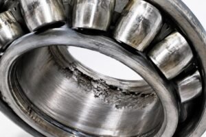Close-up inspection of a failed spherical roller bearing showing fatigue spalling on the raceway